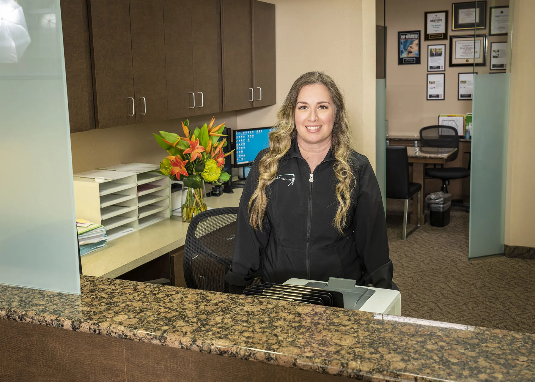 A dental assistant standing by on her desk