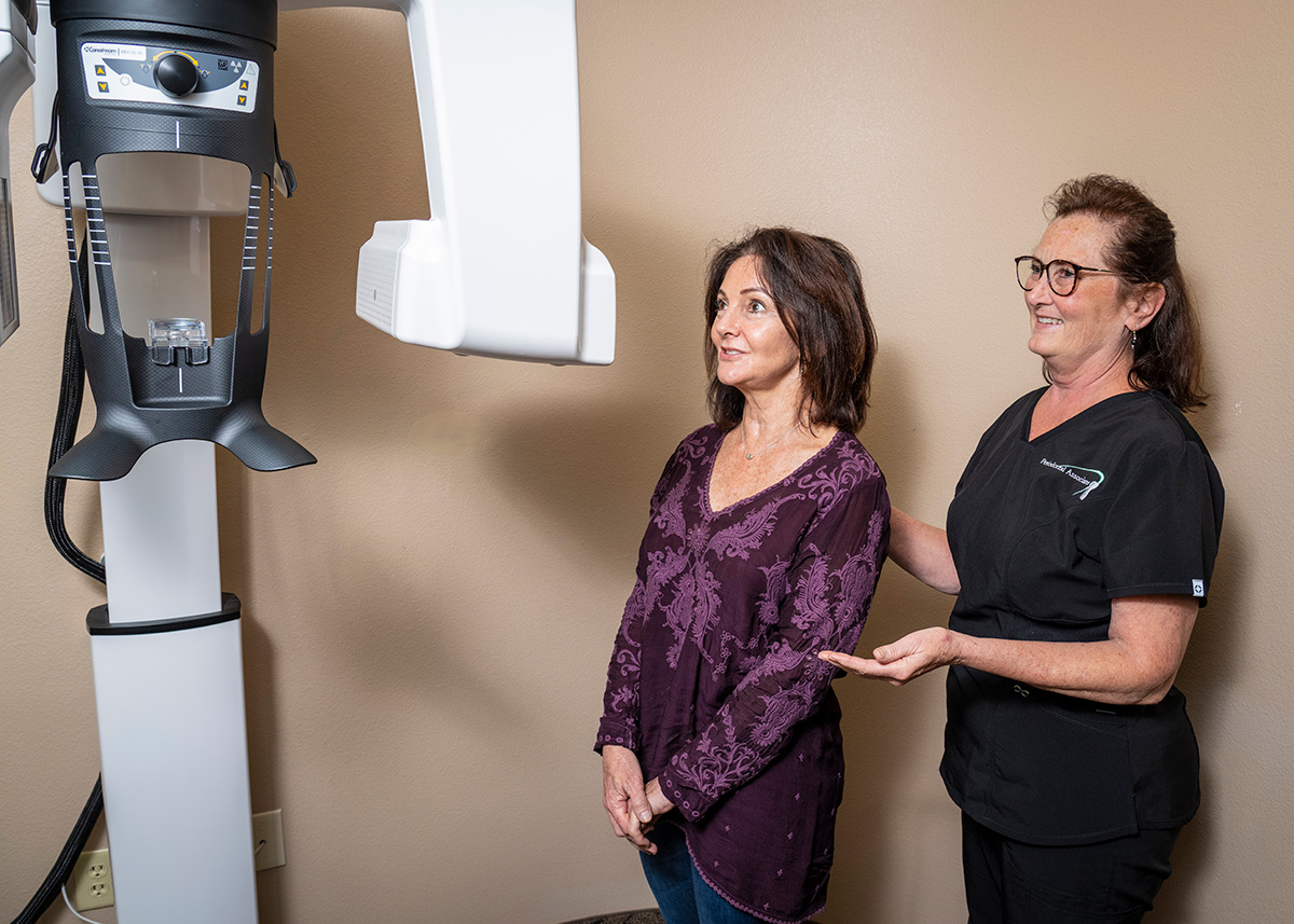 A dental assistant showing a patient a 3D scanner
