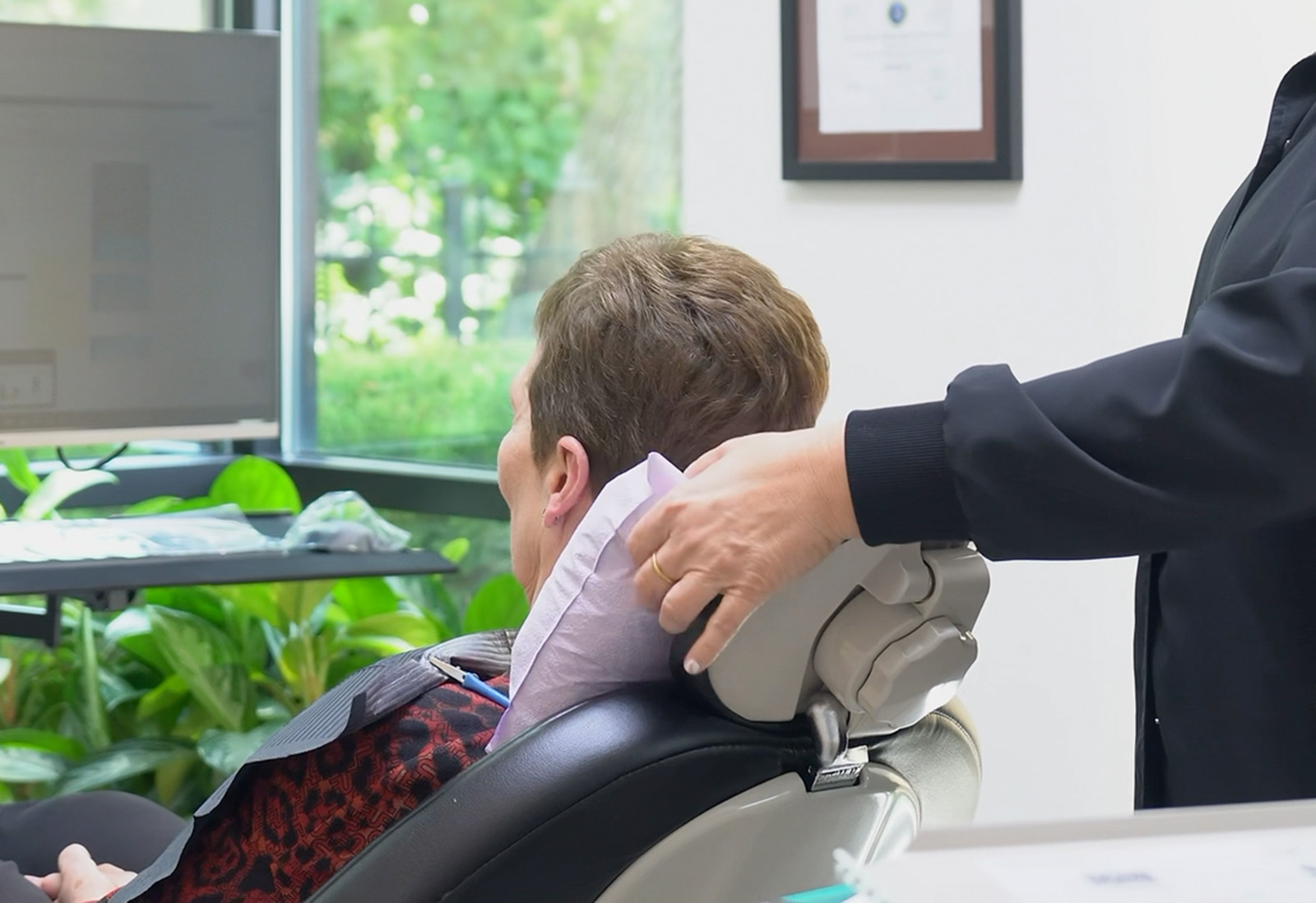 A dental assistant helping a patient rest on her chair